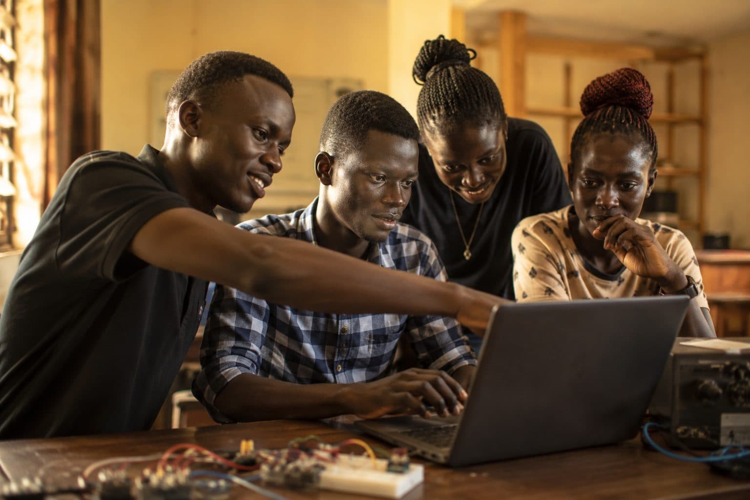 Students collaborating around a laptop at a Junub Code workshop